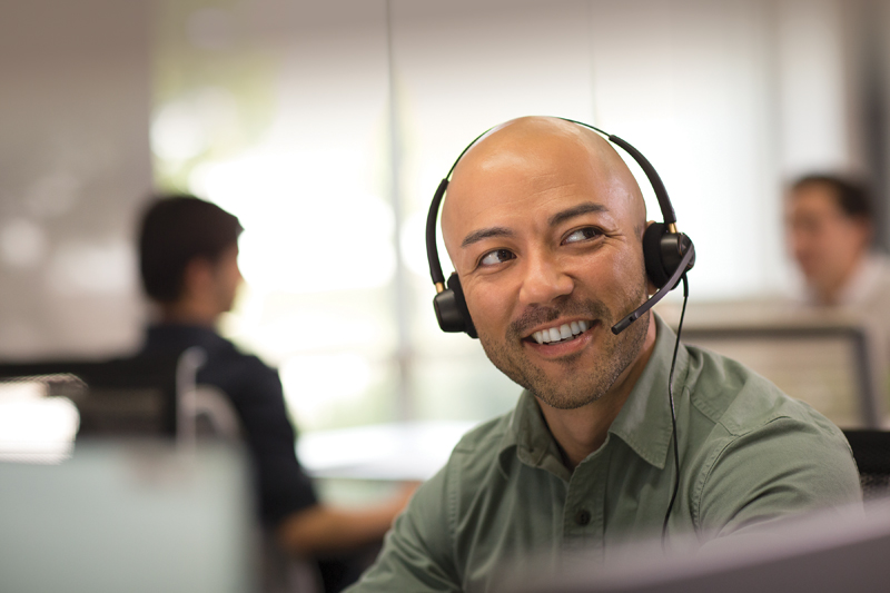 A man wearing a headset and smiling while on the job.